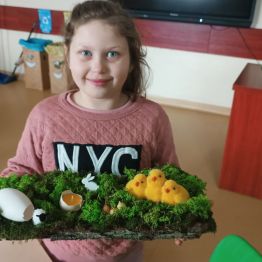 Laura ze swoją dekoracją wielkanocną na korze drewna.