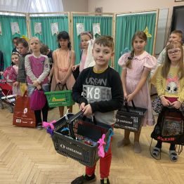 Dzieci z koszykami sklepowymi zamiast plecaków.