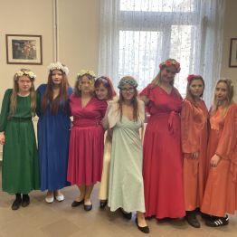 Grupka nastoletnich uczennic w eleganckich sukniach.