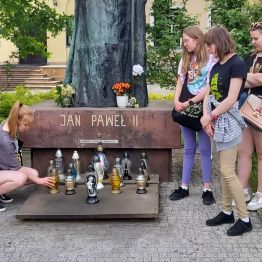 Dziewczynka zapala znicz pod pomnikiem.