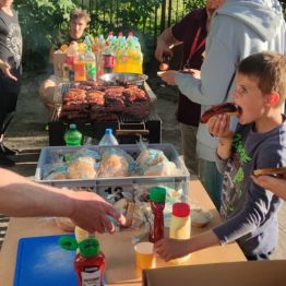 Wychowankowie jedzący kiełbaski przygotowane z grilla.