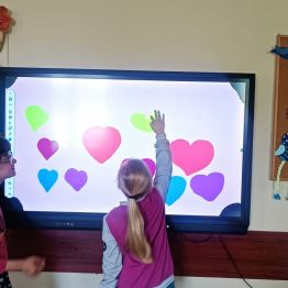 Marta i Nikola rysują na tablicy serca dla swoich rodziców.