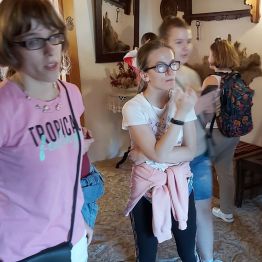 Dziewczynki słuchają wykładu o pisarzu i jego rodzinie przez panią przewodnik.