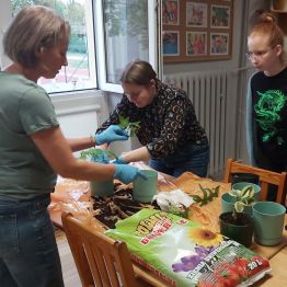 Dziewczynki pod opieką wychowawczyni sadzą kwiaty