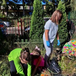 Uczniowie klas I-III wykonują prace porządkowe w ogródku szkolnym