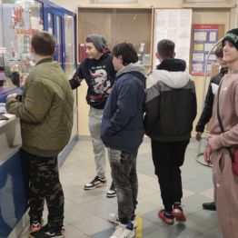 Sześciu chłopców czeka do kasy w urzędzie pocztowym.