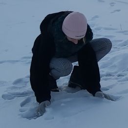 Dziewczynka zbiera śnieg na kulę.