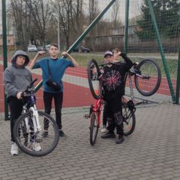 Trzech chłopców stoi przy rowerach.