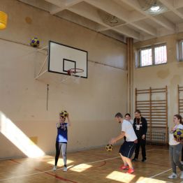 Uczniowie wykonują rzuty do kosz do gry w korfball.