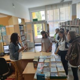 Pani bibliotekarka podczas spotkania zapoznaje uczennice z księgozbiorem oraz działalnością biblioteki. 