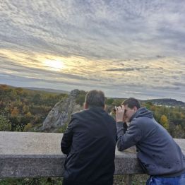 Wychowawca z wychowankiem oglądają krajobraz przez lornetkę 