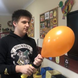 Szymon pompuje pomarańczowy balon. 