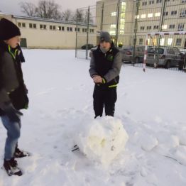 Chłopcy zbierają śnieg na kulę.