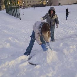 Dziewczynka zbiera śnieg na kulę.