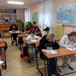 Uczniowie siedzą w ławkach i piszą Konkurs