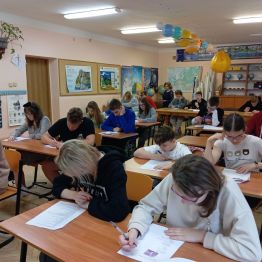 Uczniowie siedzą w ławkach i piszą Konkurs