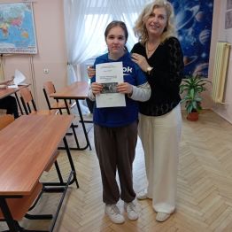 Dziewczynka stoi i oddaje gotową pracę dla nauczyciela