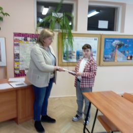 Uczeń wręcza nauczycielowi swoja pracę