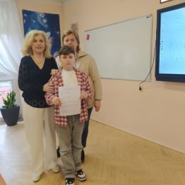 Uczeń z dwoma paniami nauczycielkami, oddaje pracę pisemną