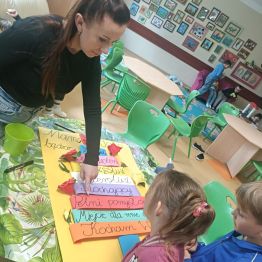 Wychowawczyni przygotowuje z dziećmi dekoracje z okazji Dnia Rodziny.