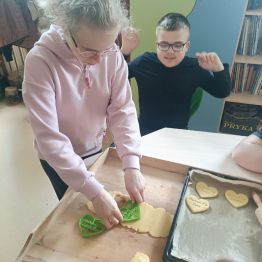 Hania wycina formy z ciasta. Kacper czeka na swoją kolej.