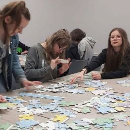 Dziewczęta i chłpocy z wielkim zaangażowaniem ukladają puzzle. 