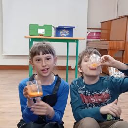 Dziewczyna trzyma szklankę z sokiem, chłopiec pije sok