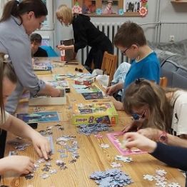 Chłopcy i dziewczyki układają puzzle. 