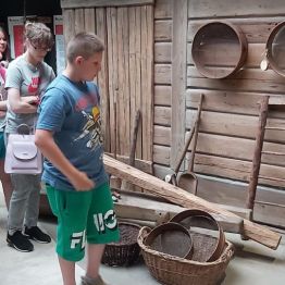 dzieci oglądają przyrządy do prac jesiennych w dawnej wsi.