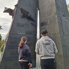 Wychowankowie czytający napisy na pomniku.