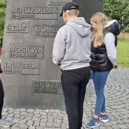 Dziewczynka i chłopiec  przy pomniku w zadumie.