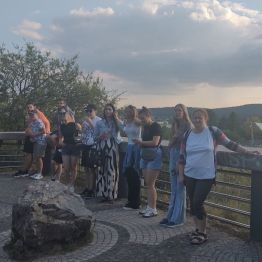 Wychowankowie pozują do zdjęcia na tarasie widokowym, podziwiając Skałkę Geologów oraz Amfiteatr.