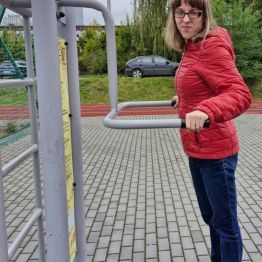 Dziewczynka wykonuje ćwiczenie ruchowe na siłowni zewnętrznej.