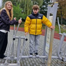 Wychowankowie wykonują różnorodne ćwiczenia ruchowe na siłowni zewnętrznej.