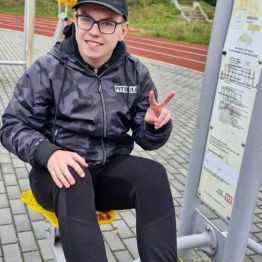 Chłopiec wykonuje ćwiczenie ruchowe na siłowni zewnętrznej.