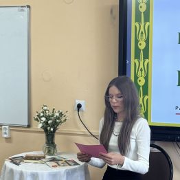 Uczennica siedzi przy stoliku i czyta wiersz
