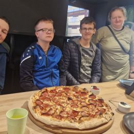 Wychowankowie pozują do zdjęcia z pizzą