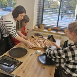 Wychowawczyni rozdziela kawałki pizzy wychowankom