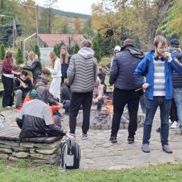 Wychowankowie przy ognisku pieką kiełbaski.