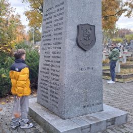 Chłopiec przy pomniku czyta napis.