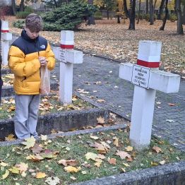 Chłopiec modli się nad grobami poległych żołnierzy.