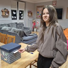 Dziewczynka wrzuca kartę głosowania do urny.