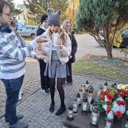 Chłopiec pomaga zapalić znicz.