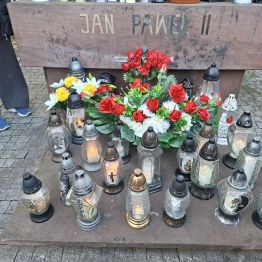 Znicze i kwiaty przed pomnikiem Jana Pawła II