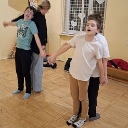 Uczestnicy zajęć wykonują doświadczenie ruchowe w formie latającego samolotu.