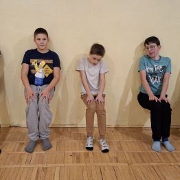 Wychowankowie oparciu plecami o ścianę próbują utrzymać równowagę.