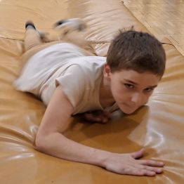 Wychowanek  przesuwa się na brzuchu wzdłuż materacy.