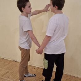 Wychowanek z otwarty oczami prowadzi chłopca, który ma zamknięte.