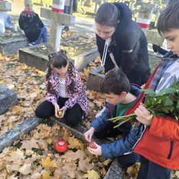 Uczniowie klas I-III zapalający znicze na mogiłach