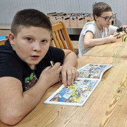 Chłopiec czyta komiks przygodowy z cyklu: Tytys, Romek i Atomek.